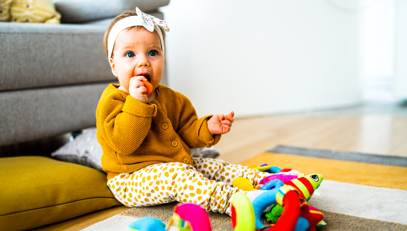 Cute baby playing with colorful toy at home